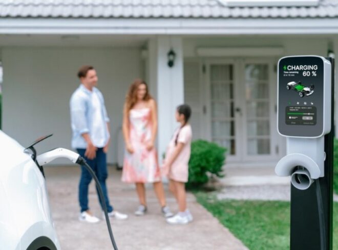 Family interacting near home EV charging station, showcasing electric vehicle charging progress in residential setting.